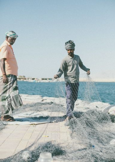 Two fishermen with nets on the shore